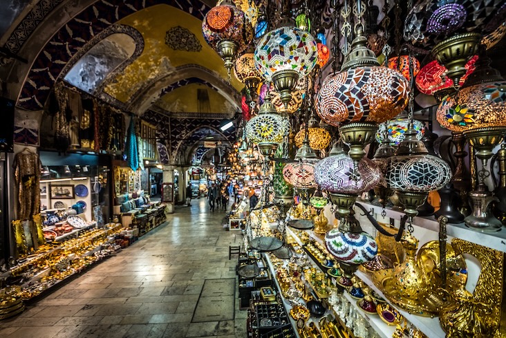 Lanterns hang outside a stall at the Grand Bazaar.  Other stores selling an array of items are visible in the background.