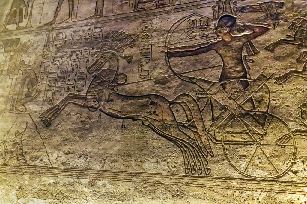 A relief from Abu Simbel Temple showing Ramses II riding in a chariot during the battle of Qadesh.  Ramses has his bow drawn as little men run from his rearing horses.