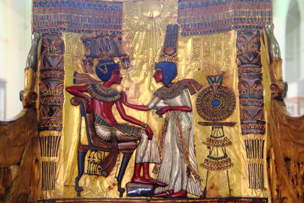 This colorful carving from Pharaoh Tutankhamun's (King Tut) tomb shows the Pharaoh seated on a throne.  The Pharaoh gazes into the eyes of Queen Ankesenamun, who stands in the center with her hand on his shoulder.